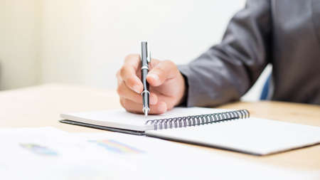 Cheerful businessman taking notes while working in the office.