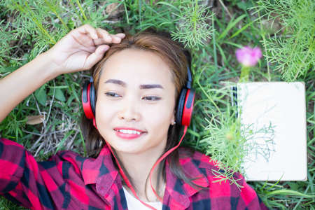 A young girl lying on the grass listening to music, relax on soft and blurred background