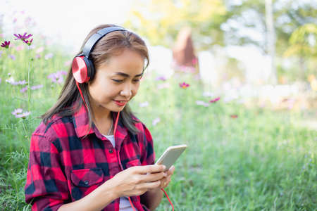 A young girl lying on the grass listening to music, relax on soft and blurred backgroundの写真素材