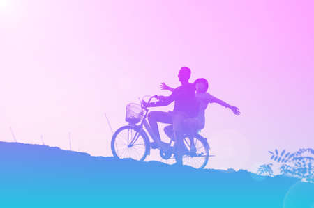 silhouette of couple driving bike happy time sunset
