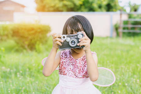 Cute little happy girl with vintage photo camera outdoorsの写真素材