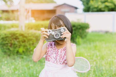 Cute little happy girl with vintage photo camera outdoorsの写真素材