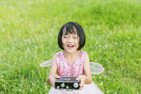 Cute little happy girl with vintage photo camera outdoorsの写真素材