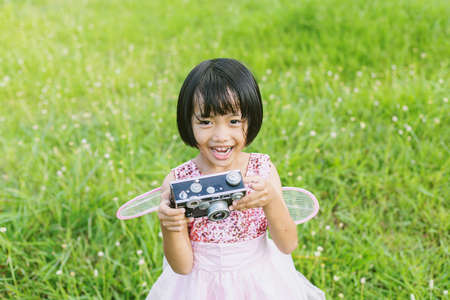 Cute little happy girl with vintage photo camera outdoorsの写真素材
