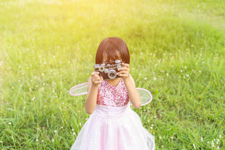 Cute little happy girl with vintage photo camera outdoorsの写真素材