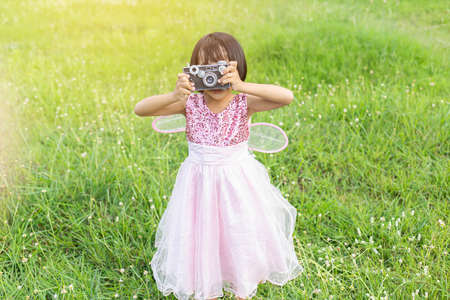 Cute little happy girl with vintage photo camera outdoorsの写真素材