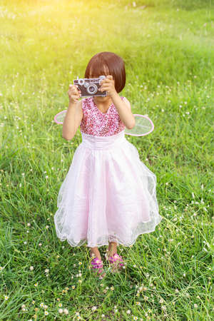 Cute little happy girl with vintage photo camera outdoorsの写真素材