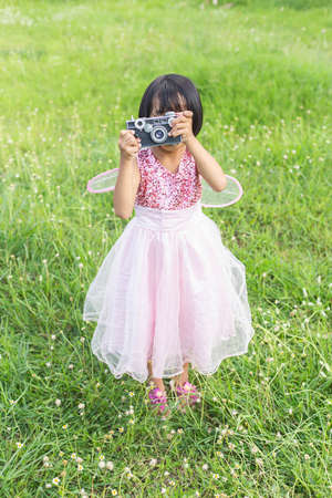 Cute little happy girl with vintage photo camera outdoorsの写真素材