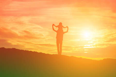 Mother encouraged her daughter out of the shadows at sunset.の写真素材