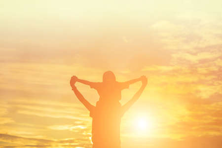 Mother encouraged her daughter out of the shadows at sunset.の写真素材