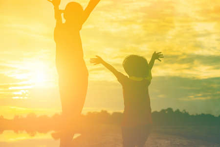 Mother encouraged her daughter out of the shadows at sunset.の写真素材