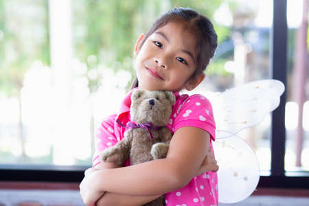 Cute little girl sitting swings , teddy bear sitting with her,little girl pointed to the tree.の写真素材