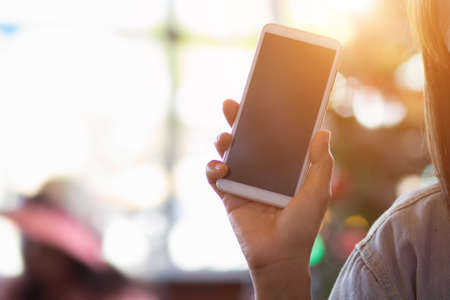 Woman holding mobile phone on blur backgroundの写真素材
