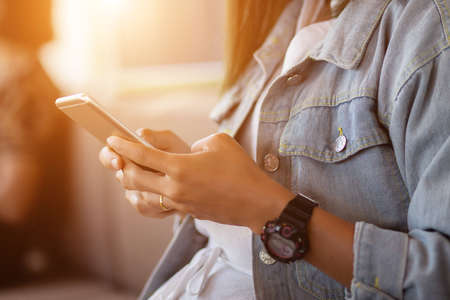 Woman holding mobile phone on blur backgroundの写真素材