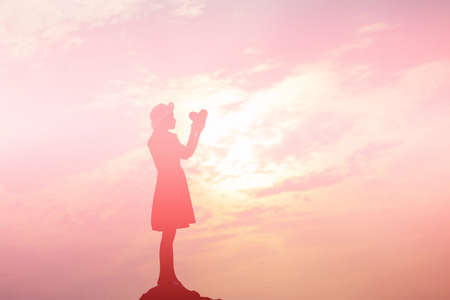 Silhouette of woman praying over beautiful sky backgroundの写真素材