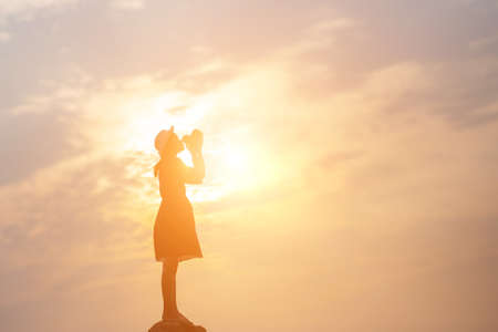 Silhouette of woman praying over beautiful sky backgroundの写真素材