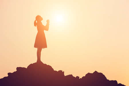 Silhouette of woman praying over beautiful sky backgroundの写真素材