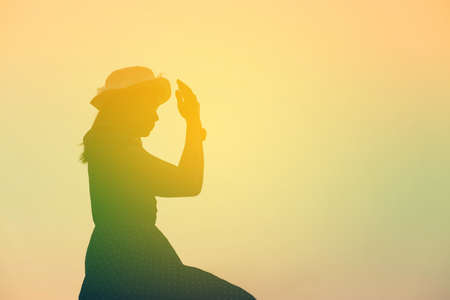 Silhouette of woman praying over beautiful sky backgroundの写真素材