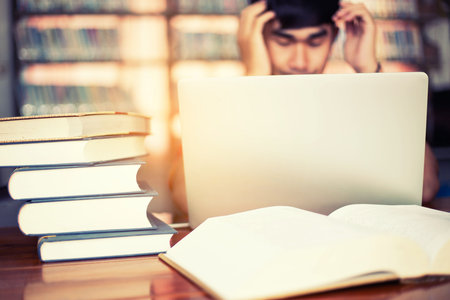 The young man is studying for knowledge in the libraryの写真素材