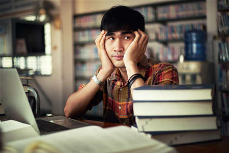 The young man is studying for knowledge in the libraryの写真素材