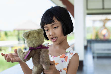 Little child girl is reading a book in evening in dark with a toy bear stock photoの写真素材