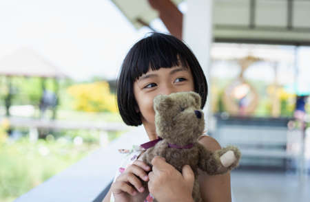 Little child girl is reading a book in evening in dark with a toy bear stock photoの写真素材