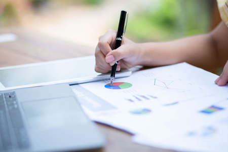 Image of document with charts on background of male and female working , business conceptの写真素材