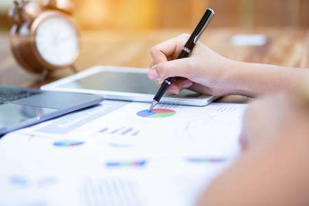 Image of document with charts on background of male and female working , business conceptの写真素材