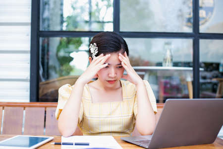 Young woman sitting in a cafe with her laptop, Stressful for work.