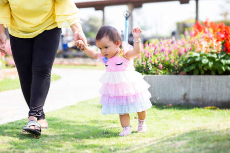 Mother holding daughter's hand for a walk in the gardenの写真素材