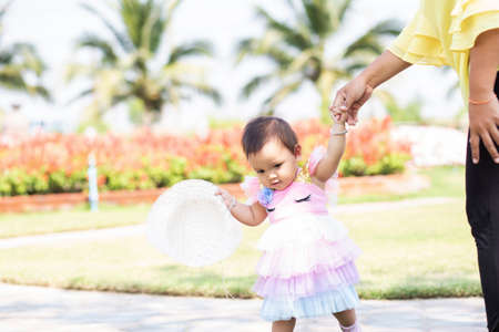 Mother holding daughter's hand for a walk in the gardenの写真素材