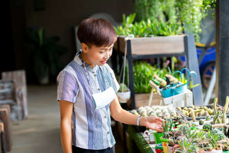 Beautiful young customer selecting fresh flowers in Parisian flower shop or on marketの写真素材