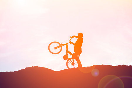 Silhouette of a cyclist on the top of the mountain at sunsetの写真素材