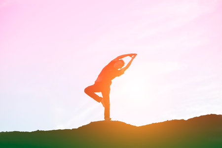 Silhouette of a man practicing yoga at sunset sky background.の写真素材
