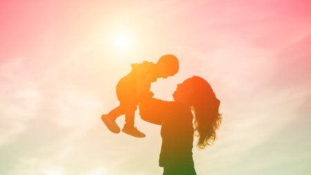 Mother encouraged her son outdoors at sunset, silhouette conceptの写真素材