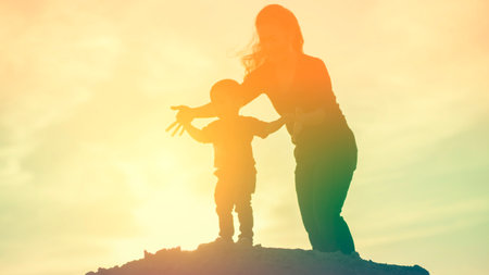 Mother encouraged her son outdoors at sunset, silhouette conceptの写真素材