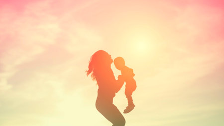 Mother encouraged her son outdoors at sunset, silhouette conceptの写真素材