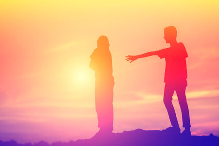Silhouette of two young people greeting each other with sunset sky backgroundの写真素材