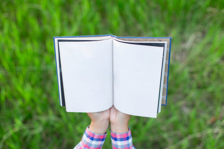 Happy woman lying on green grass reading a book in the park (outdoors)の写真素材