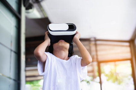 Young girl kid child play virtual reality game hold vr glasses and surprised. Cyber space and virtual gamingの写真素材