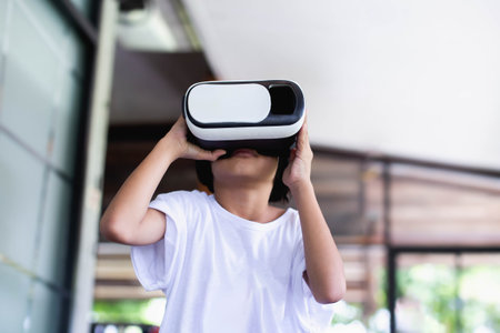 Young girl kid child play virtual reality game hold vr glasses and surprised. Cyber space and virtual gamingの写真素材