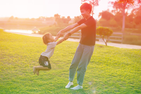 Happy harmonious family outdoors. mother throws baby up, laughing and playing in the summer on the...