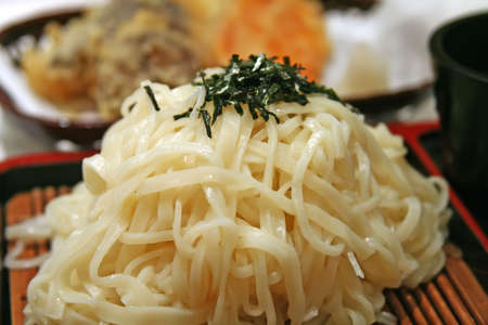 Cold japanese udon noodles on a bamboo mat with sprinkles of seaweedの写真素材