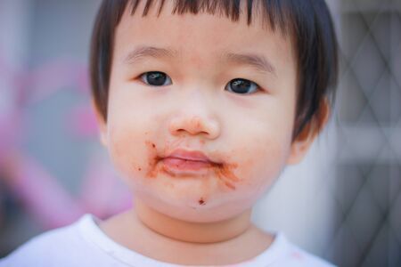 Little kids love to eat chocolate in the mouth dirty.の写真素材