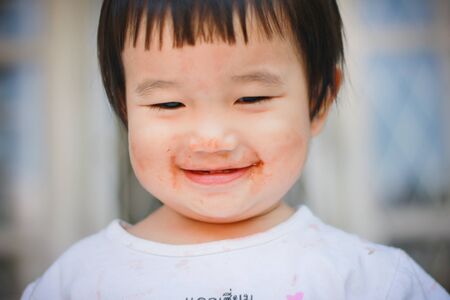 Little kids love to eat chocolate in the mouth dirty.の写真素材