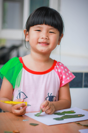 Lovely girl with leaves in the work of art , Children and art from the leaves. , Leaves on art , Cute little girl with Craft for kids,Crafts with kids , selective focus , Thailand.の写真素材