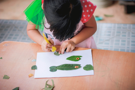 Lovely girl with leaves in the work of art , Children and art from the leaves. , Leaves on art , Cute little girl with Craft for kids,Crafts with kids , selective focus , Thailand.の写真素材