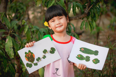 Lovely girl with leaves in the work of art , Children and art from the leaves. , Leaves on art , Cute little girl with Craft for kids,Crafts with kids , selective focus , Thailand.の写真素材