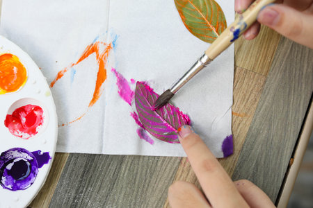 Asian cute girl doing leaf art , 
A cute Asian girl makes a leaf stamping art , 
Color stamping with leaves , art from natural materials
 , selective focus ,beautiful sea with us, Thailand.の写真素材