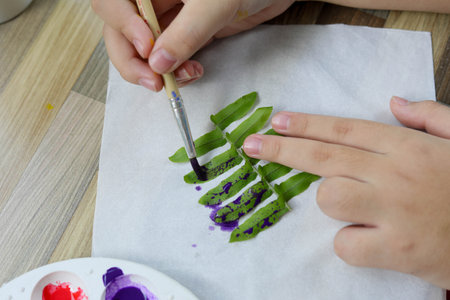 Asian cute girl doing leaf art , 
A cute Asian girl makes a leaf stamping art , 
Color stamping with leaves , art from natural materials
 , selective focus ,beautiful sea with us, Thailand.の写真素材